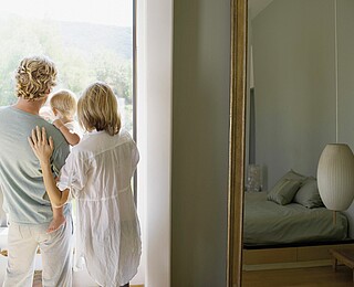 Couple and baby son looking out window --- Image by © Ocean/Corbis